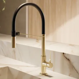 Black and brass kitchen mixer beside a pale stone sink